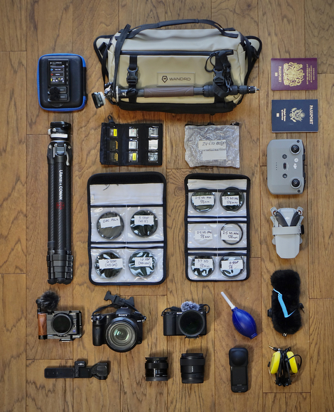 the contents of a travel bag laid out on a wooden floor.