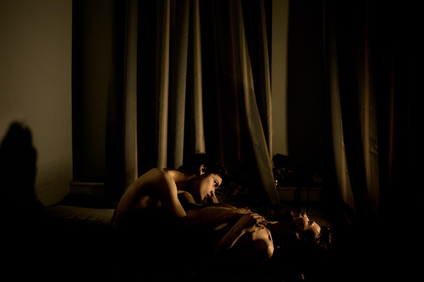 a woman laying on a bed in a dark room.
