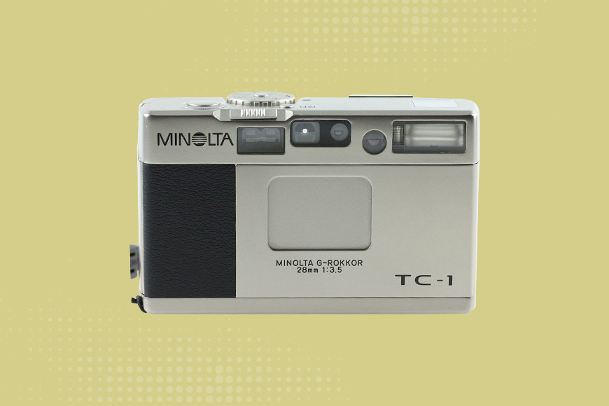 Minolta TC-1 camera with a yellow background.