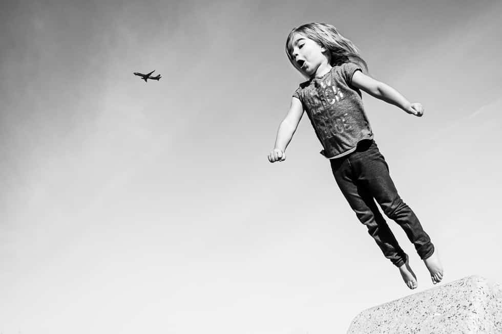 a little girl jumping off a rock into the air.