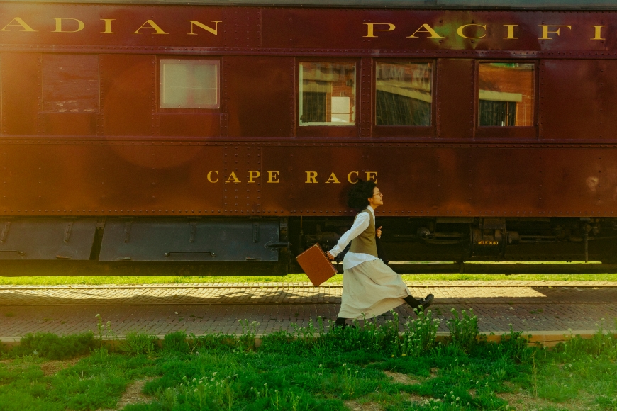 a woman in a dress is walking by a train.