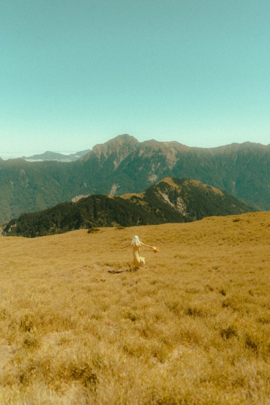 a person in a field with mountains in the background.