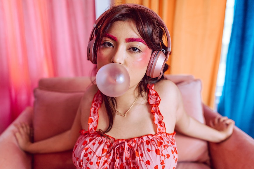 a woman blowing a bubble with headphones on.