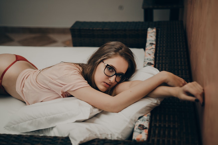 a woman laying on a bed wearing glasses.