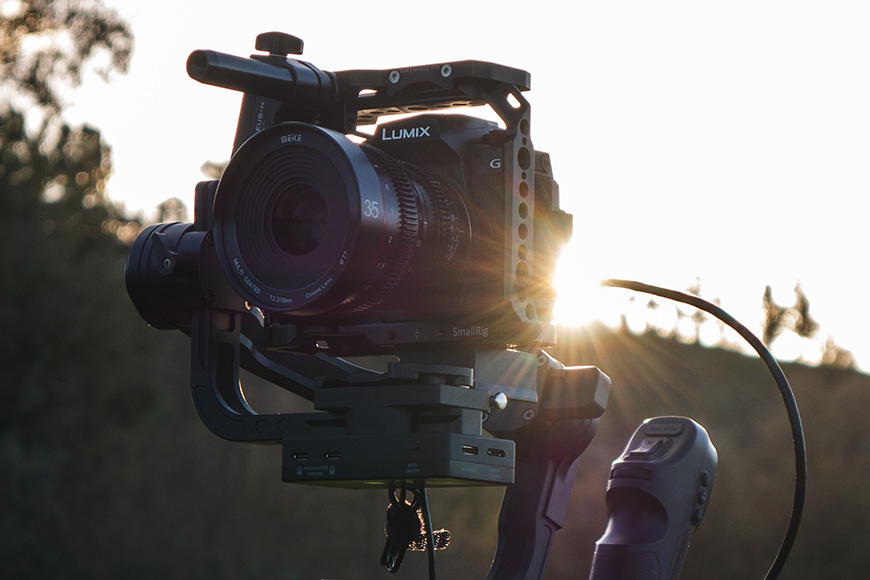 a camera attached to a rig cage with the sun behind it.