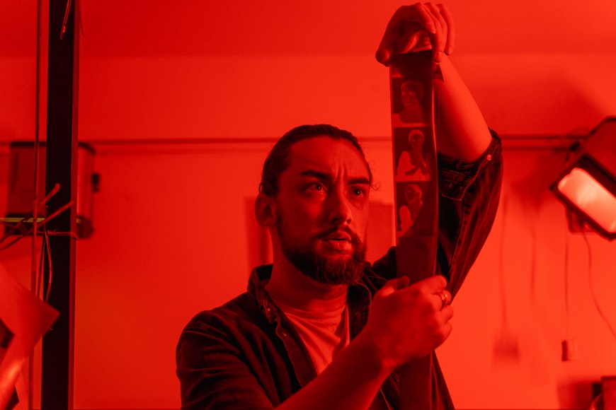 a man in the darkroom holding a negative film
