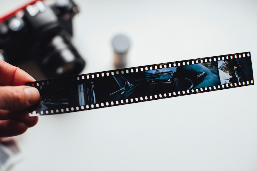 a person holding a film strip with a camera in the background.
