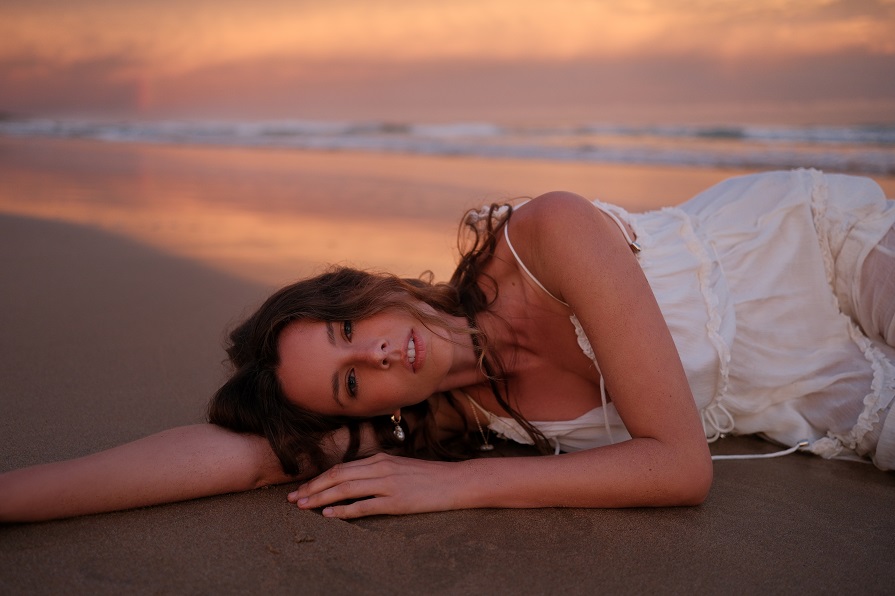 a beautiful woman laying on top of a sandy beach.