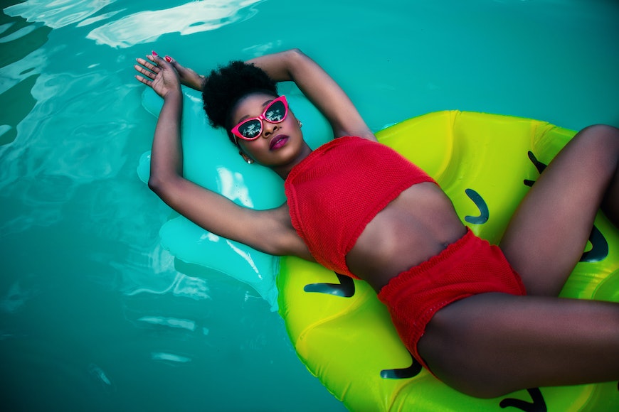 a woman in a red top and red shorts floating on an inflatable raft.