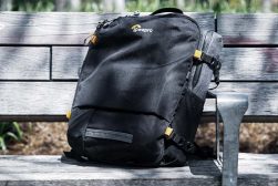 a black backpack sitting on top of a wooden bench.