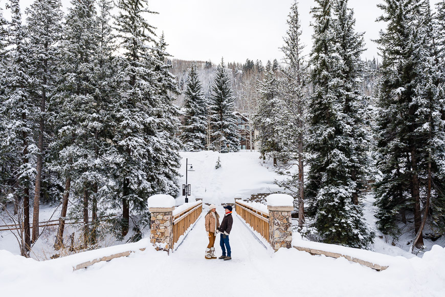 two people standing on a bridge in the snow.