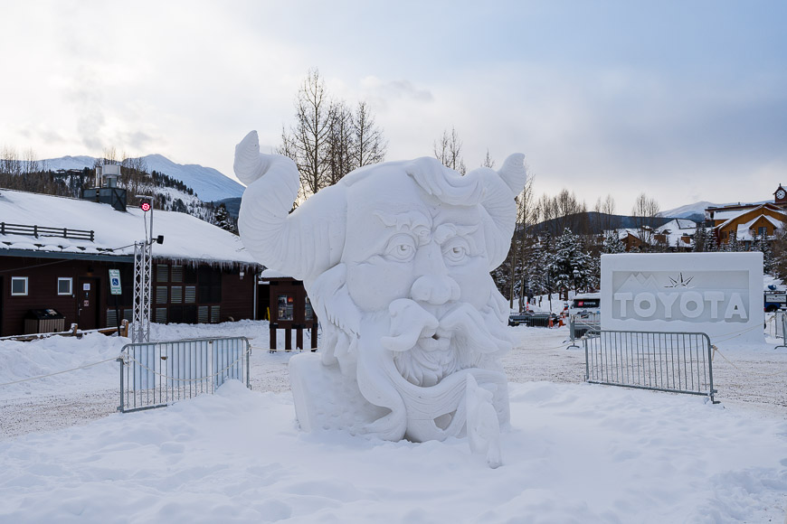 a snow sculpture of a dragon in front of a hotel.