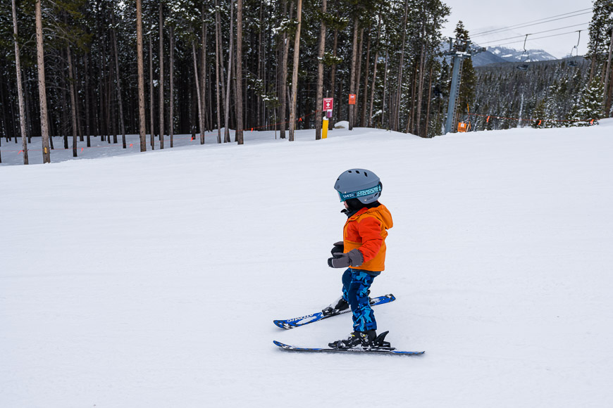 a young child riding skis down a snow covered slope.