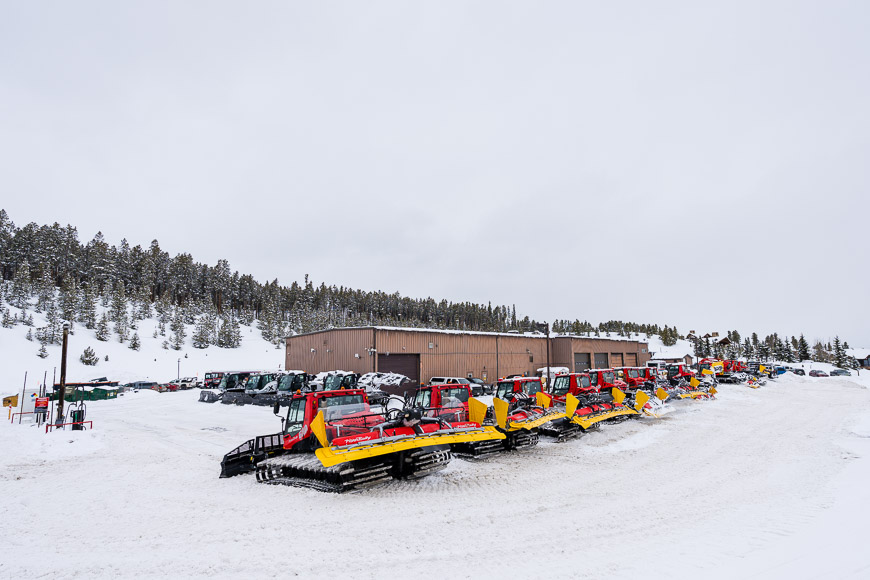 a row of snow plow parked in front of a building.