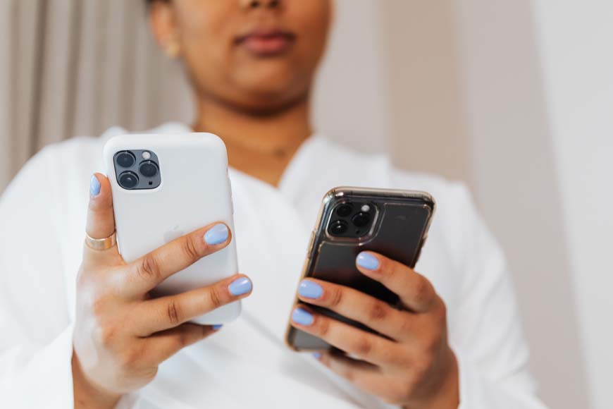 a woman holding an iphone in each hand. 