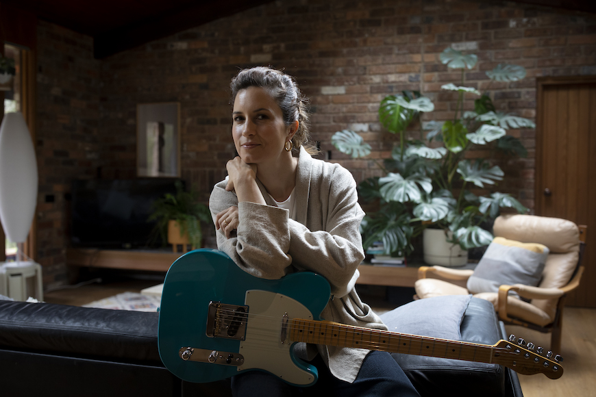 a woman sitting on a couch holding a guitar.