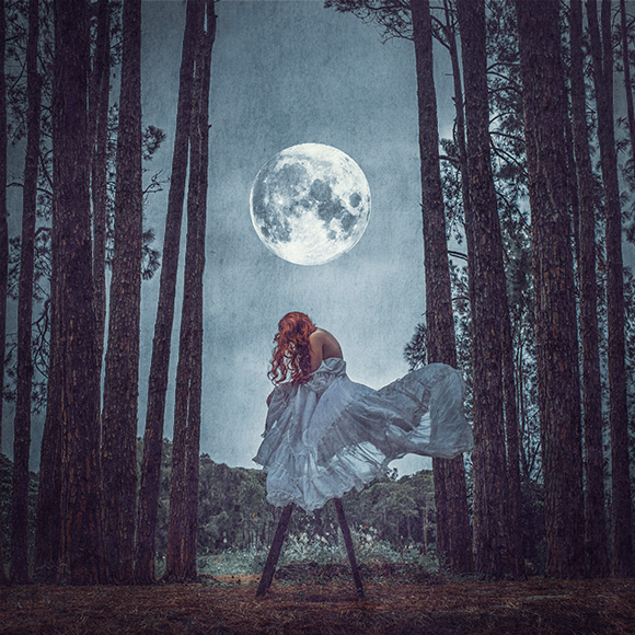 a woman standing in the middle of a forest under a full moon.