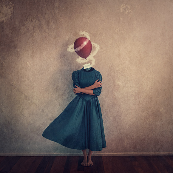 a woman standing in front of a wall with a red ball on her head.