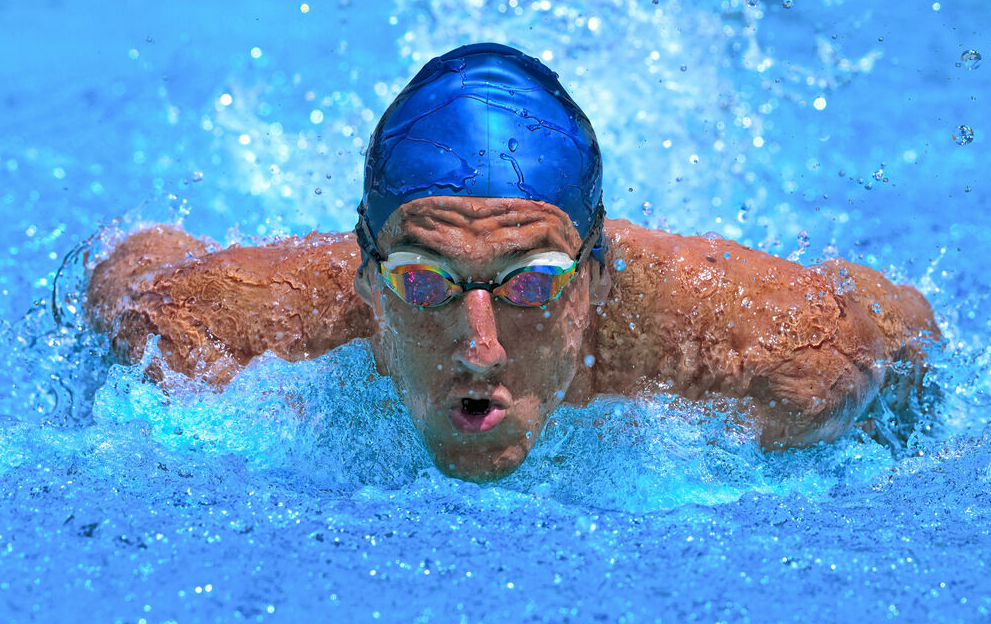 a man swimming in a pool with goggles on.