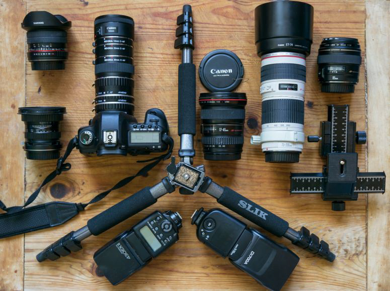 a collection of different cameras and canon lens accessories laid out on a table.