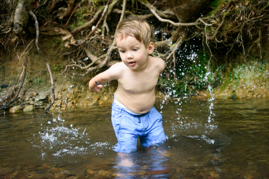 a young boy standing in a body of water.