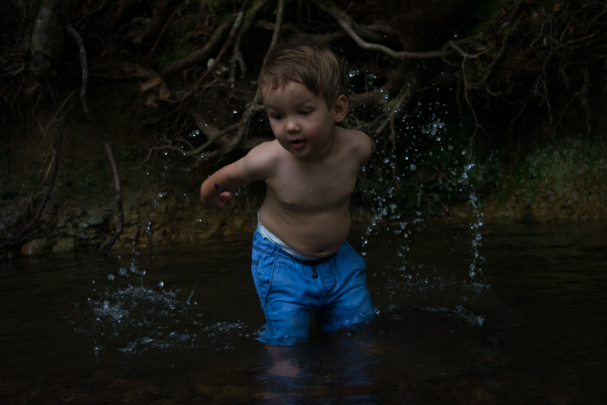a young boy standing in a body of water.