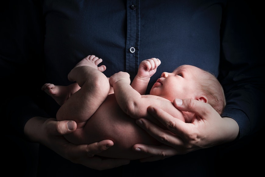 a person holding a baby in their hands.