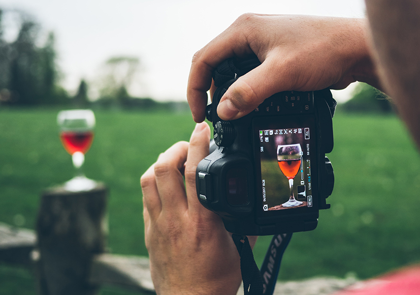 a person taking a picture of a glass of wine.