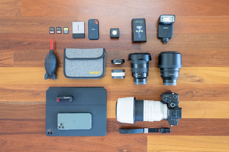 a camera, flash camera, flash drive, and other items laid out on a.