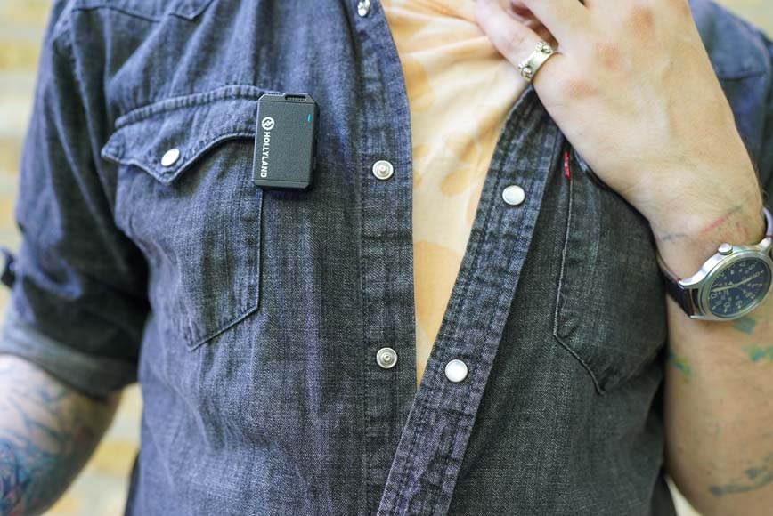 a man in a denim shirt is wearing a lav mic on his shirt