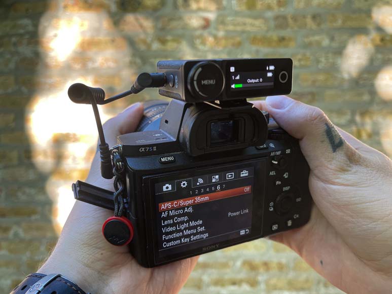 a person holding a camera with a brick wall in the background.