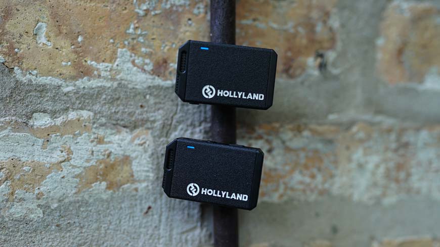 a close up of two black lav microphones on a brick wall.
