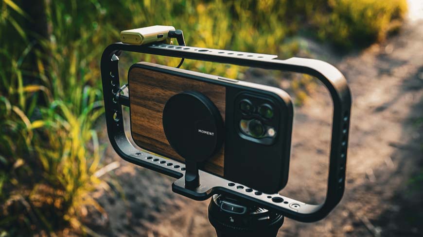 Iphone camera attached to a tripod in a field.