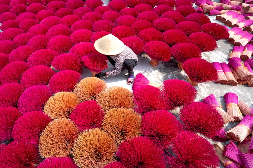 a man is working on a pile of red sticks.