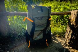 A backpack sitting on a log in the woods.
