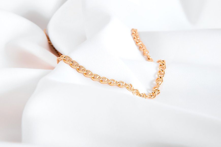 a close up of a gold chain on a white cloth.
