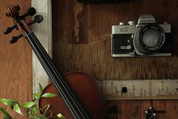 a violin and a camera on a wooden table.