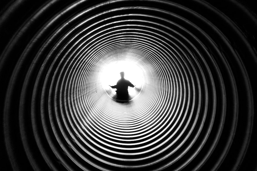 a black and white photo of a man standing in a tunnel.