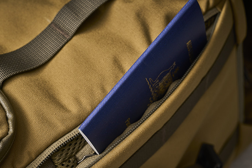 a tan backpack with a blue passport in it.