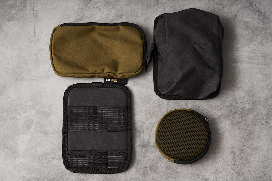 a black, brown, and green toiletry bag on a concrete floor.