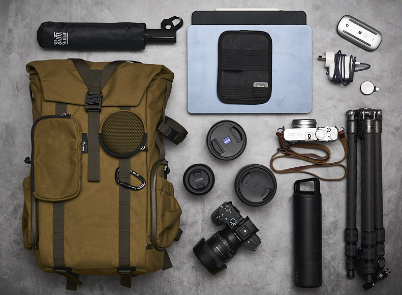 a backpack with a camera and other items laid out on a concrete floor.