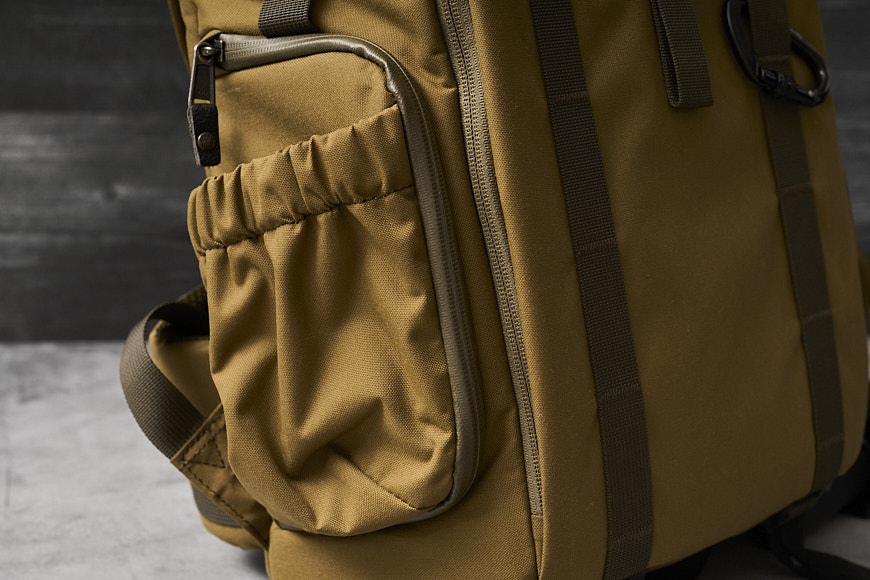 a tan backpack on a grey background.