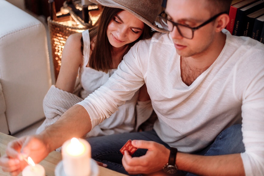 a man and woman lighting a candle on a coffee table.