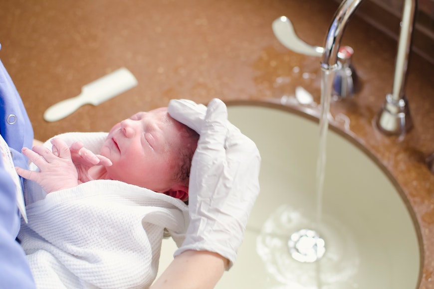 a nurse is washing a newborn in a sink.