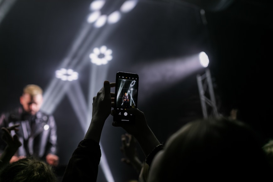 a person taking a picture of a concert with a cell phone.