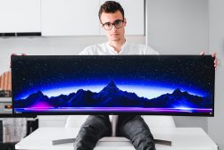 a man holding up a large monitor with a mountain scene on it.