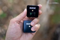 a person holding a small lavalier mic receiver with the word rode on it.