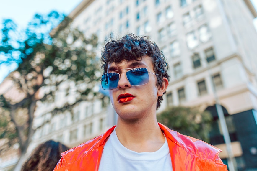 a young man in an orange jacket and red lipstick.