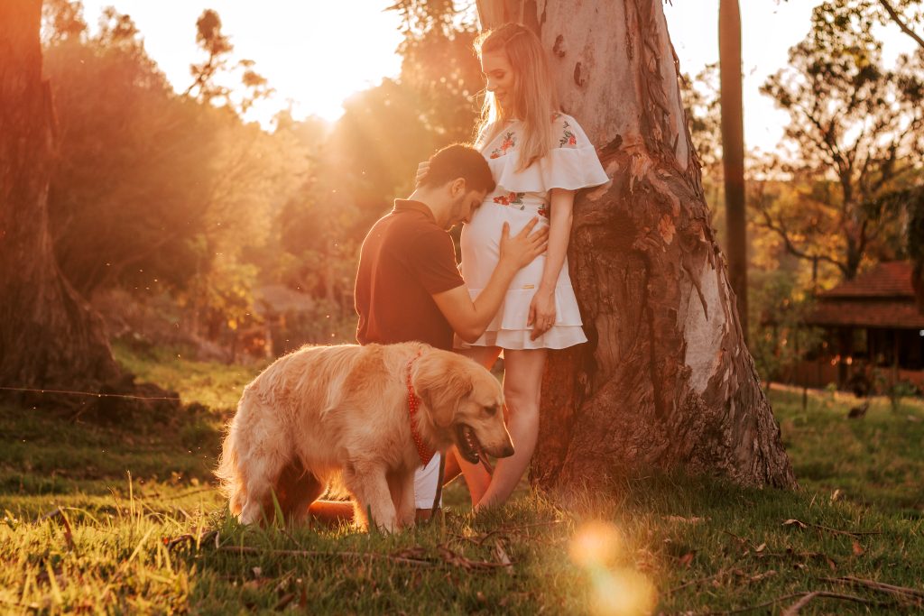 a man and woman with a dog in front of a tree.
