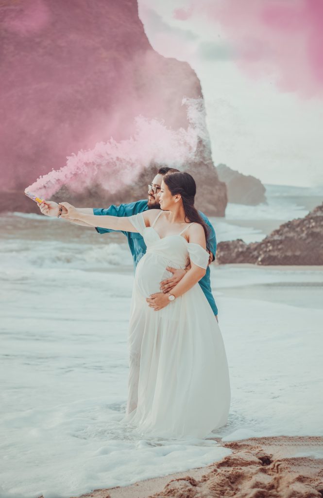 a bride and groom are holding pink smoke on the beach.
